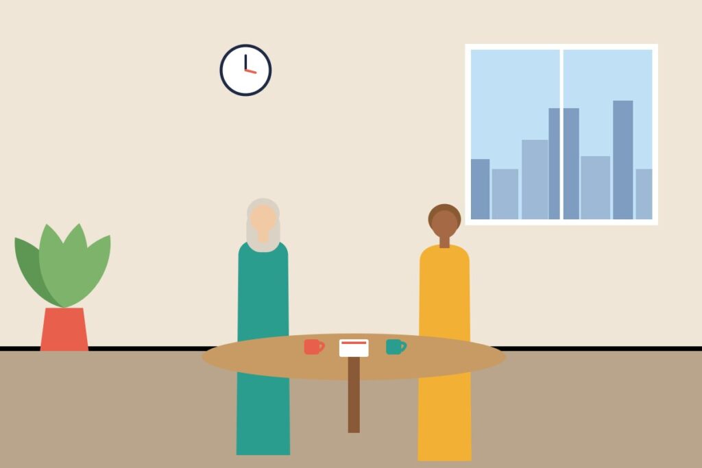 Two colleagues talking over coffee at a small round table
